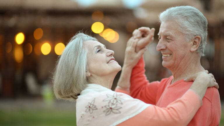 Senior couple smiling and dancing outside