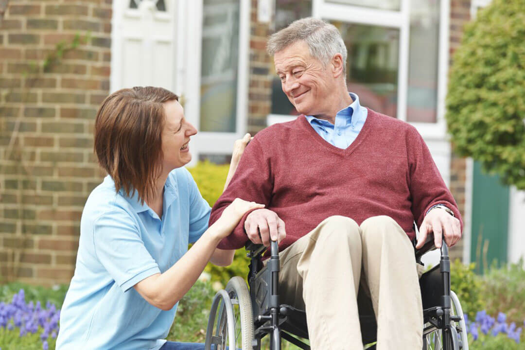 Caregiver helps man in wheelchair